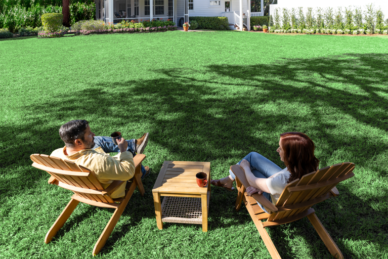 A couple sitting on a beautiful lawn cared for by TruGreen experts.