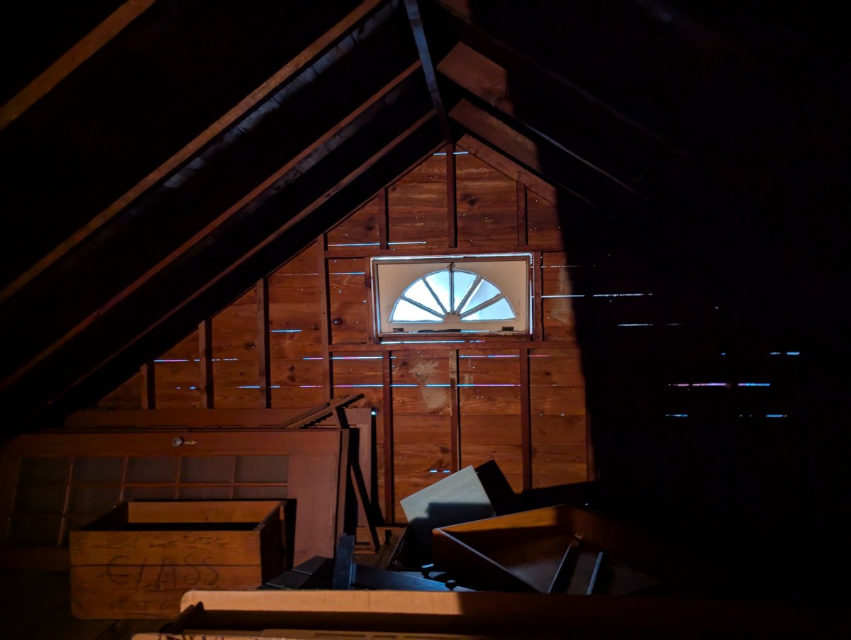 View from Inside Attic While Siding Is Removed, Where You Can See Light Coming Through Between Wood Planks