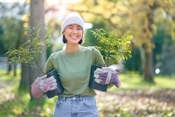 Woman portrait, plant and gardening in a park with trees in nature environment, agriculture or garden. Happy volunteer planting for growth, ecology and sustainability for community on Earth day.
