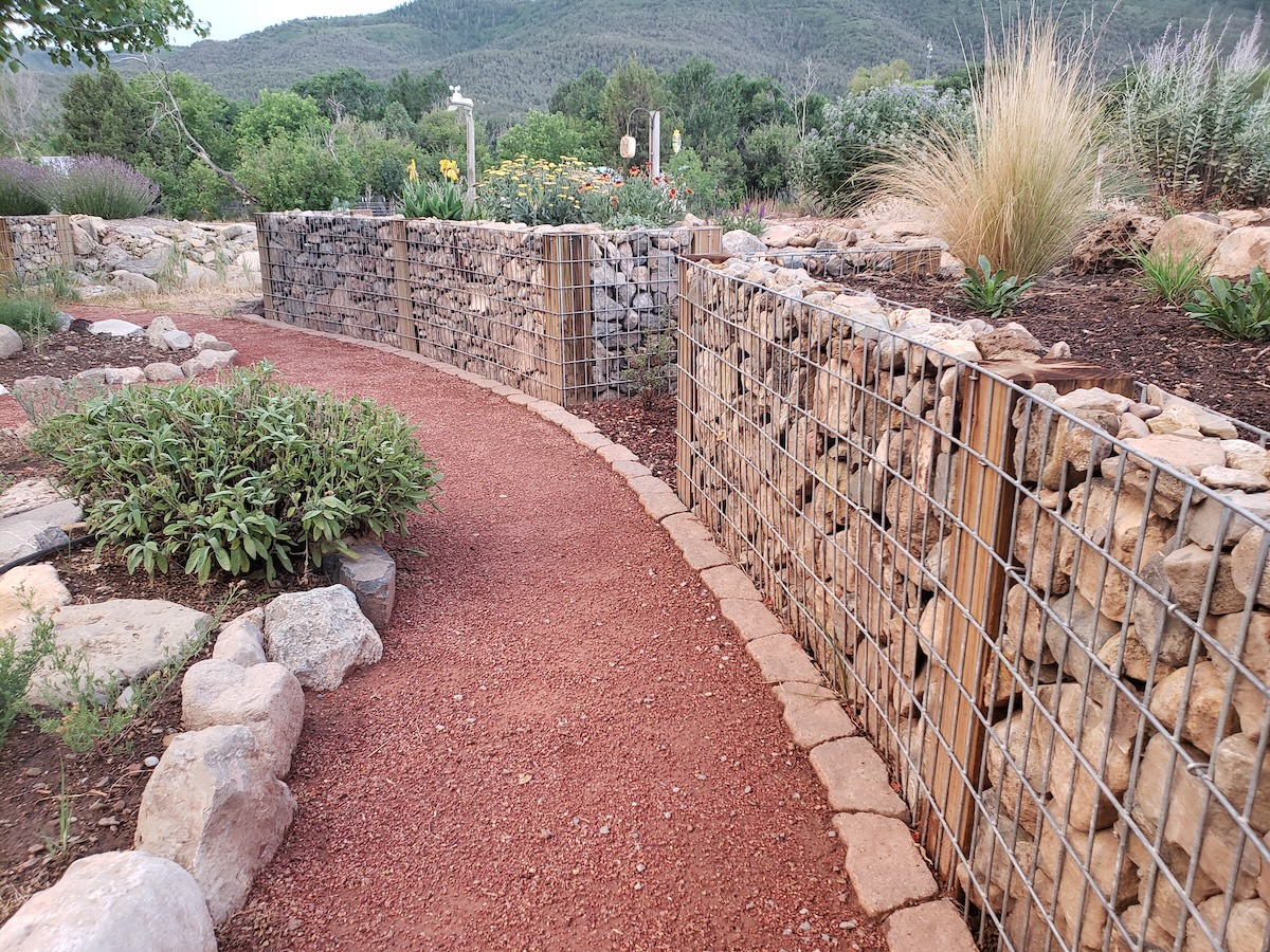 Crusher fines path next to large gabion walls in a home landscape.