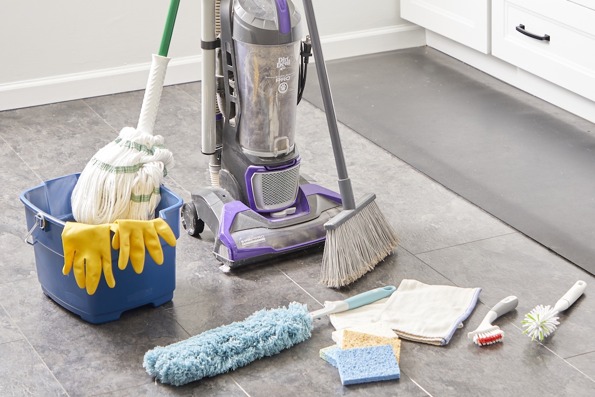 Cleaning tools such as a vacuum, bucket, mop and others collected on a kitchen floor.
