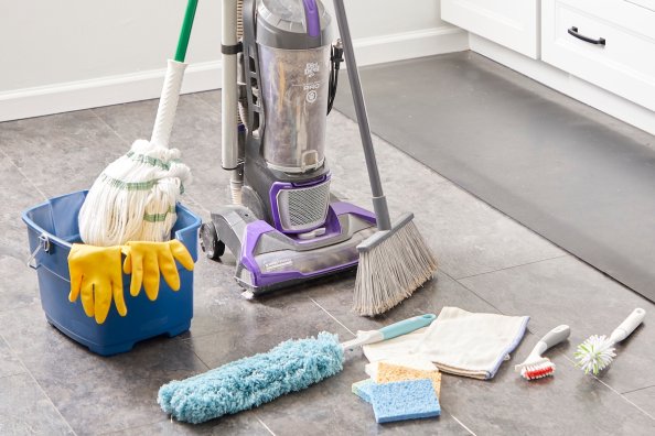 Cleaning tools such as a vacuum, bucket, mop and others collected on a kitchen floor.