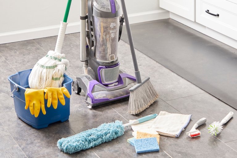Cleaning tools such as a vacuum, bucket, mop and others collected on a kitchen floor.