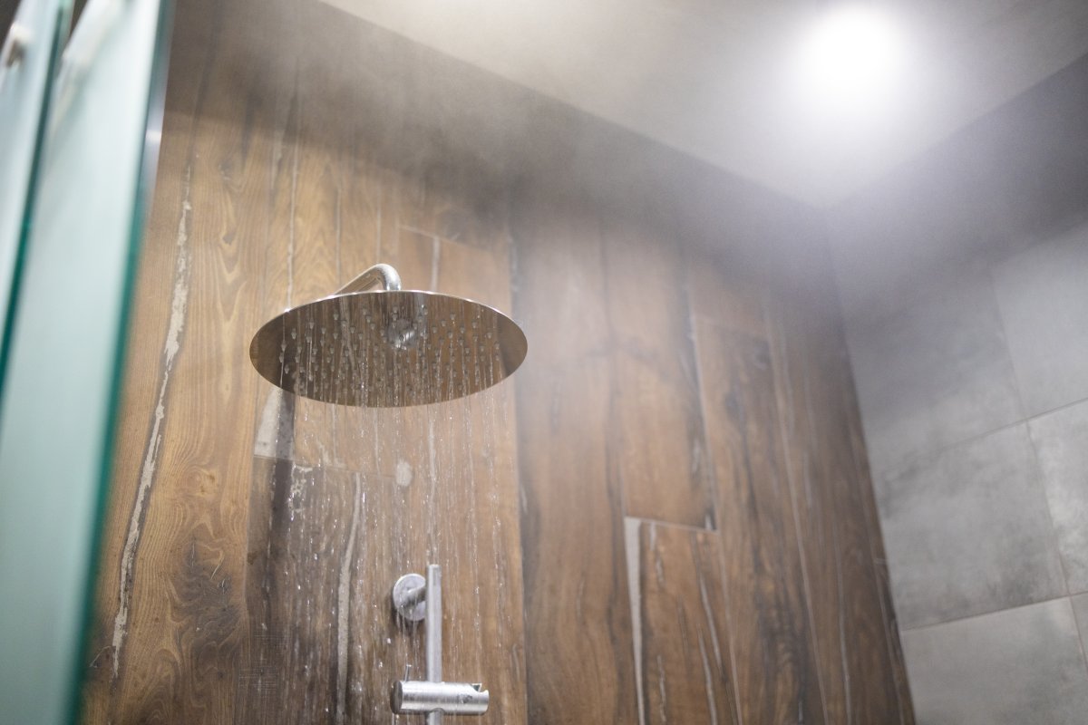 Close up of steam and hot water flowing from shower in the bathroom interior