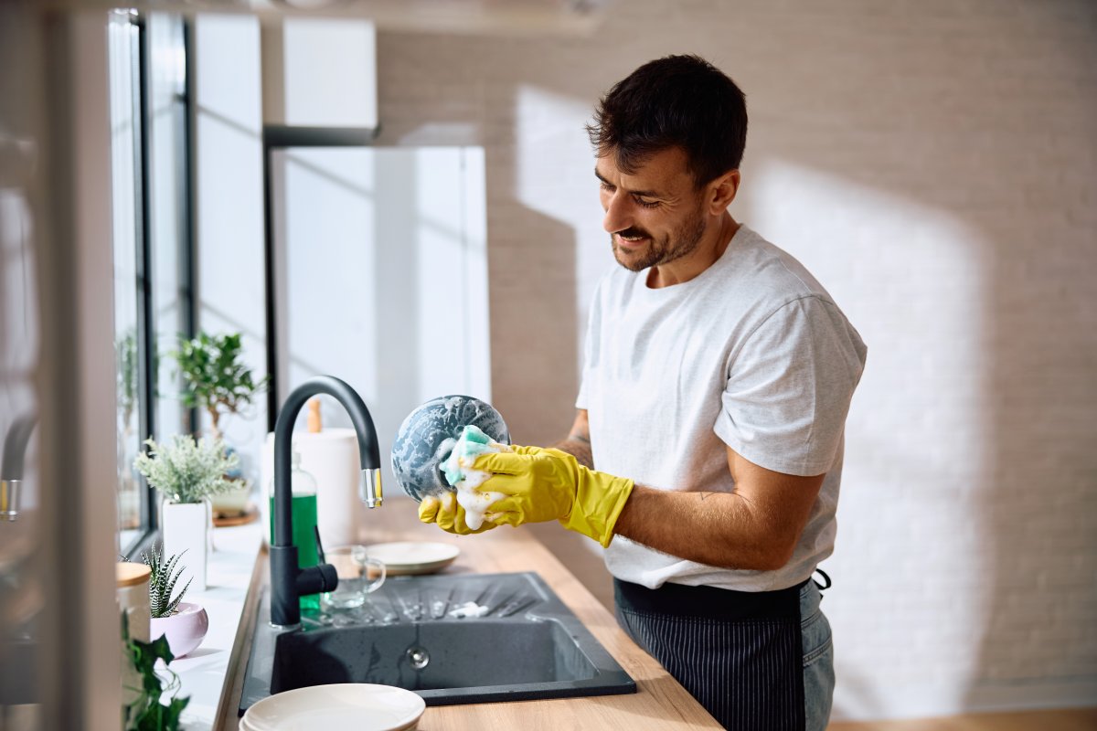 Smiling young man cooking dishes in kitchen.