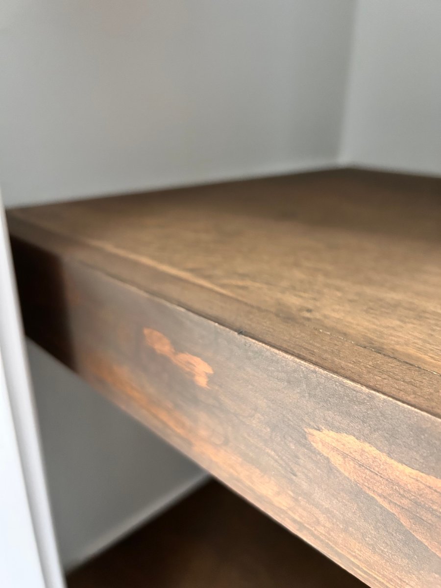 Wood cover for wire shelves in a linen closet.