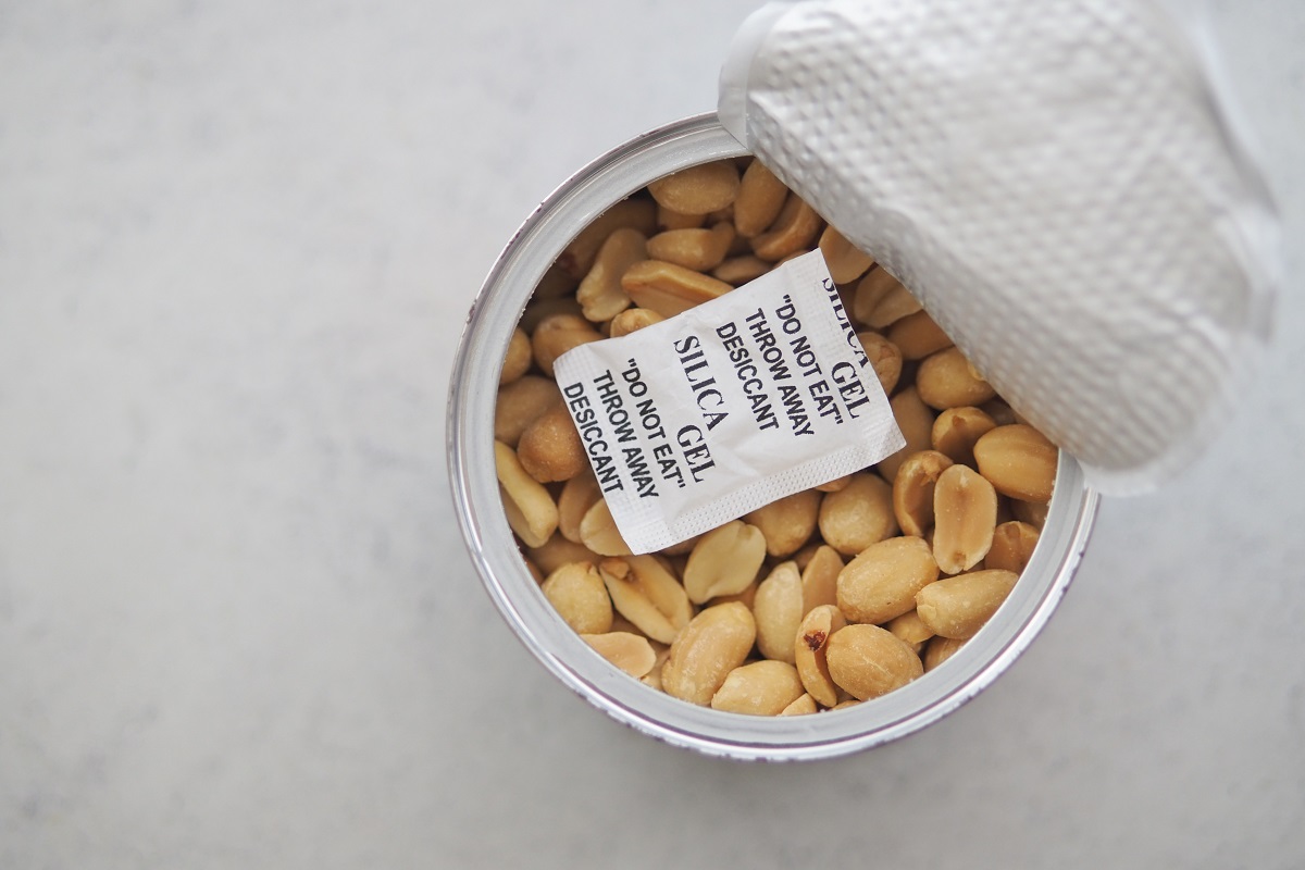 A container holds peanuts with silica gel packets on top.