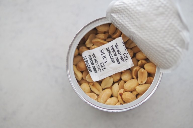 A container holds peanuts with silica gel packets on top.