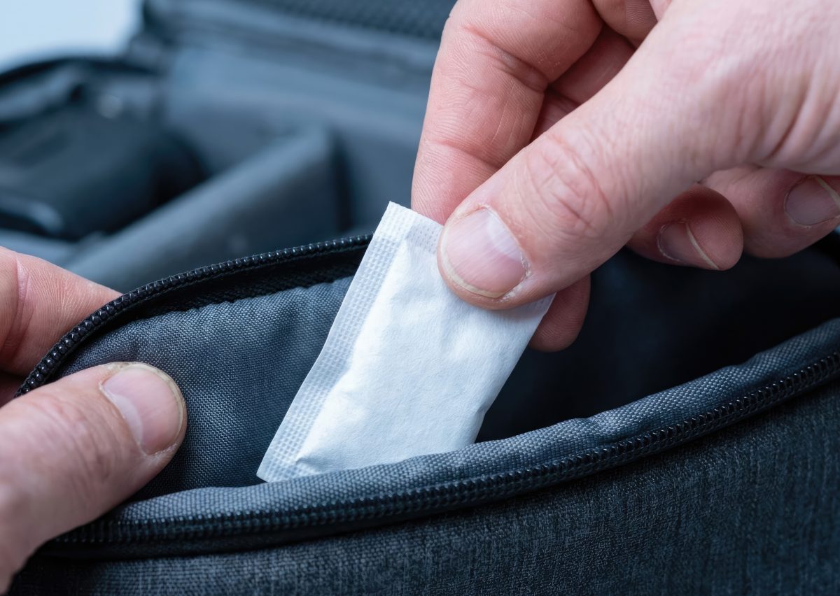 Person putting a silica packet in their camera bag.