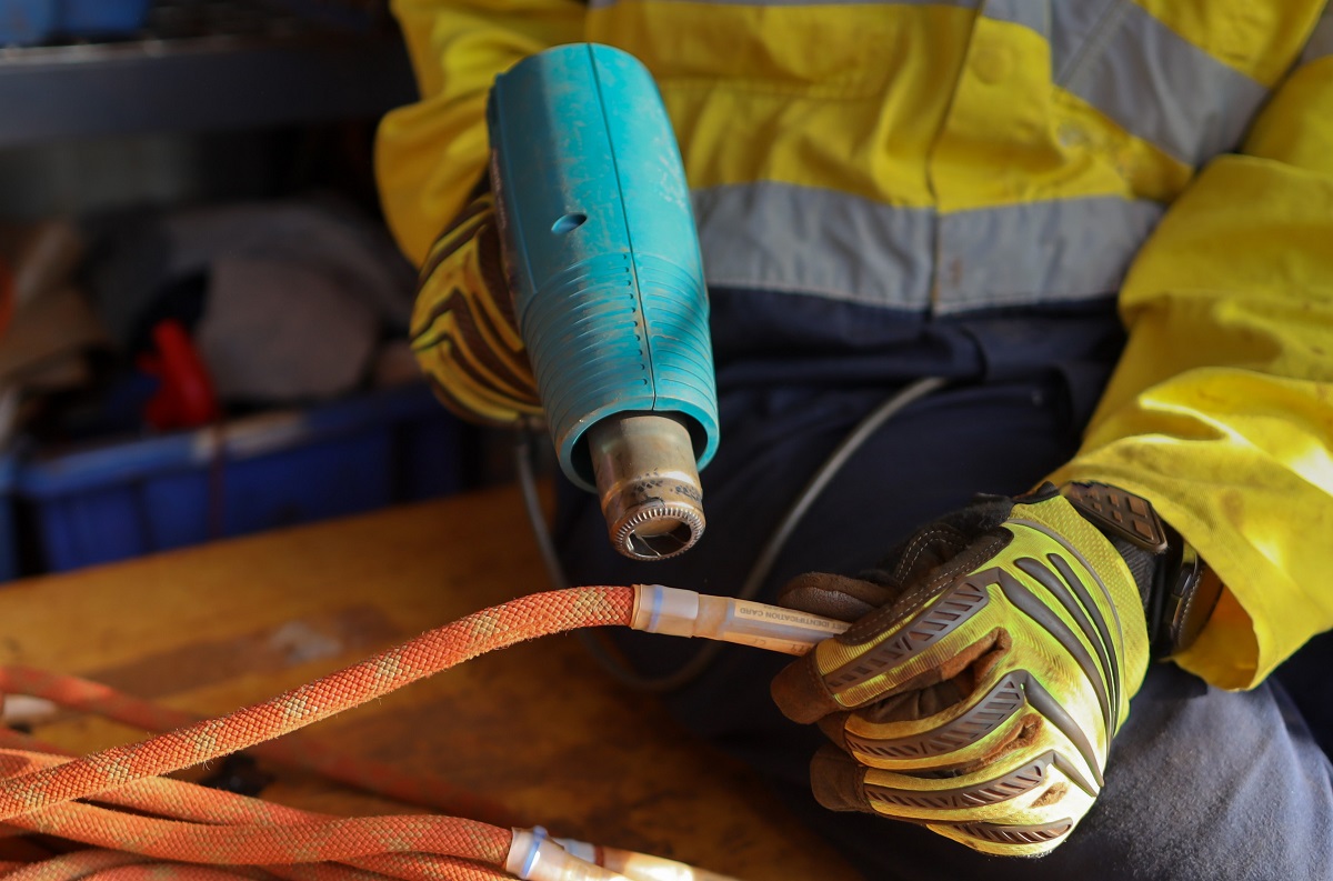 Close up view of male setting wearing a safety protective glove using a heat gun.