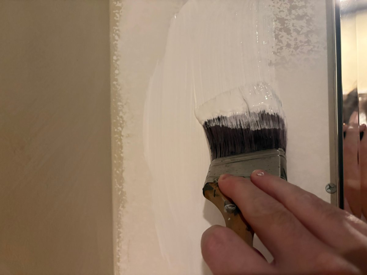 A person applying the Behr drywall plus drywall primer with a brush during testing