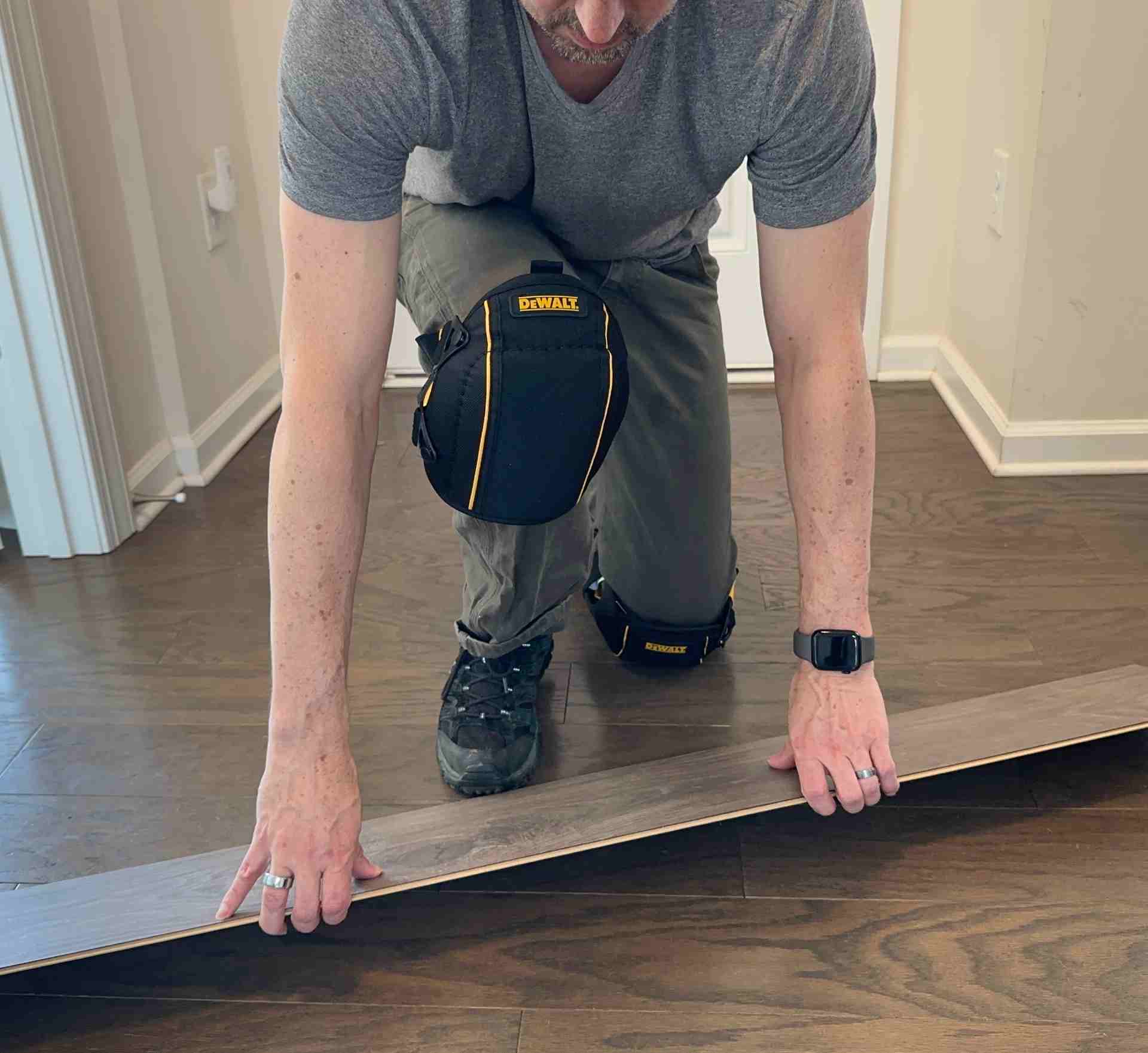 A person wearing DeWalt knee pads while installing flooring during testing