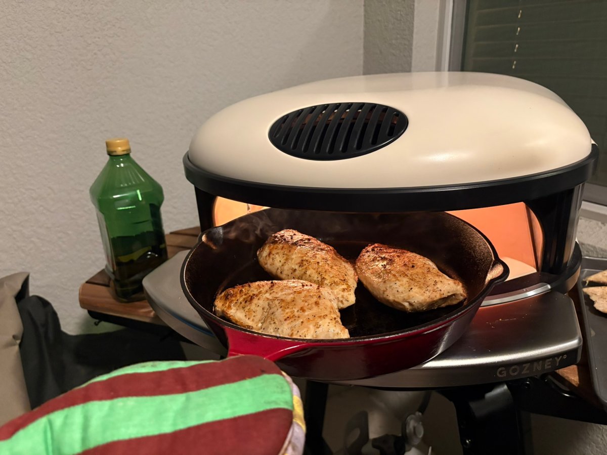 A product tester pulling a skillet of chicken out of the gozney arc XL during testing