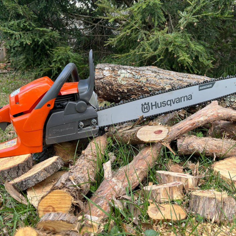 Husqvarna 24-Inch 460 Rancher Gas chainsaw on a pile of cut wood during testing