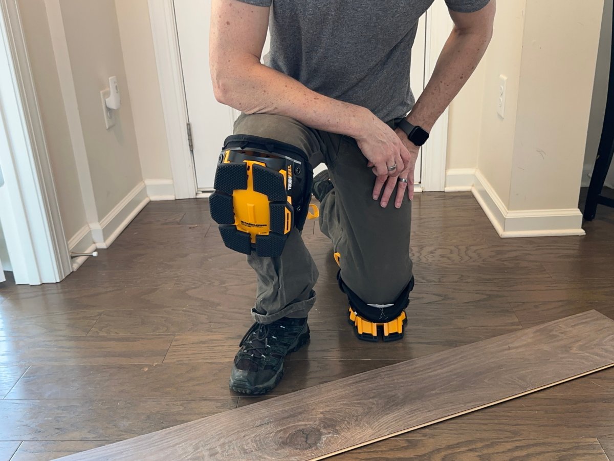 A person wearing a pair of the best knee pads while kneeling to install a panel of flooring