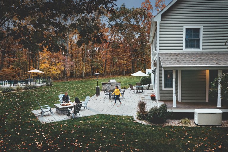 Outdoor living setup in the side yard, with propane fire pit and generator in view