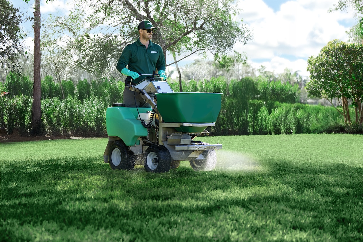 A TruGreen professional spreading fertilizer on a client's lawn.