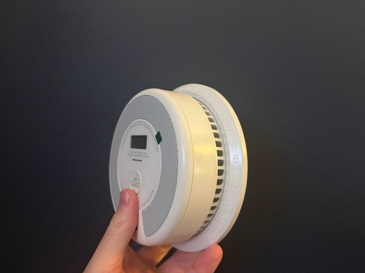 A product tester holding the X-Sense Smoke and CO alarm mount before installation and testing