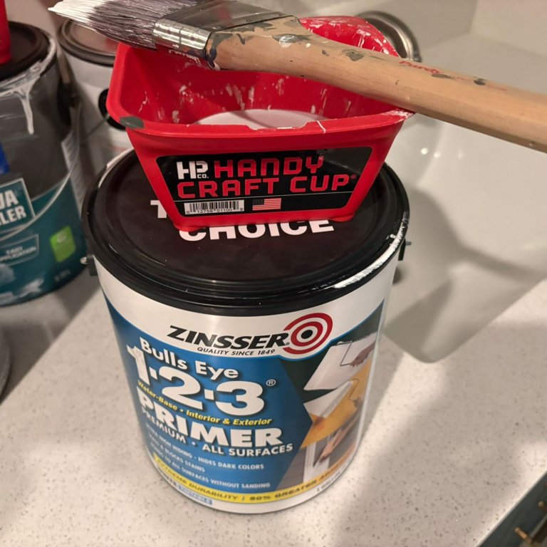 A paint bucket filled with Zinsser Bulls Eye 1-2-3 Primer and Sealer while on top of its gallon can during testing
