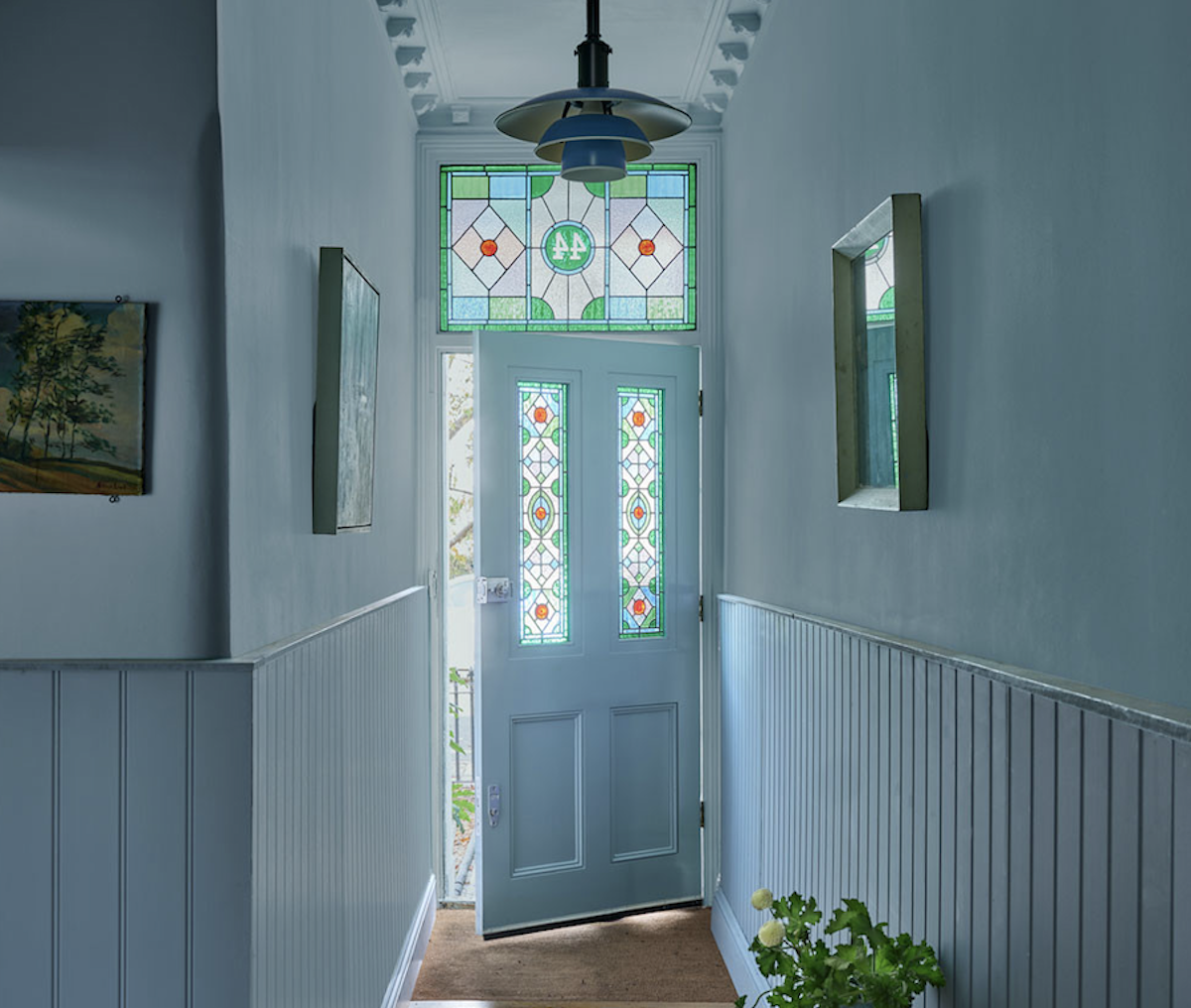 A entry hallway painted in Farrow & Ball's blue paint called "Selvedge." 