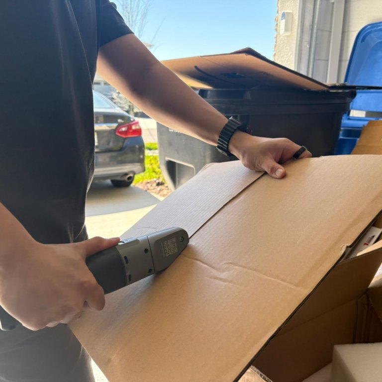 A product tester using the Boxblayde electric cardboard cutter to break down a cardboard box during testing