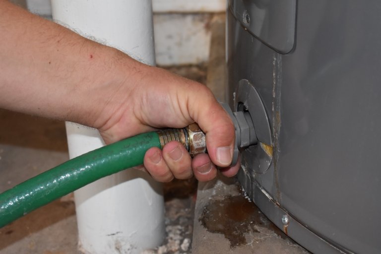 Hand Connecting Garden Hose to Drain the Water Heater . High quality photo
