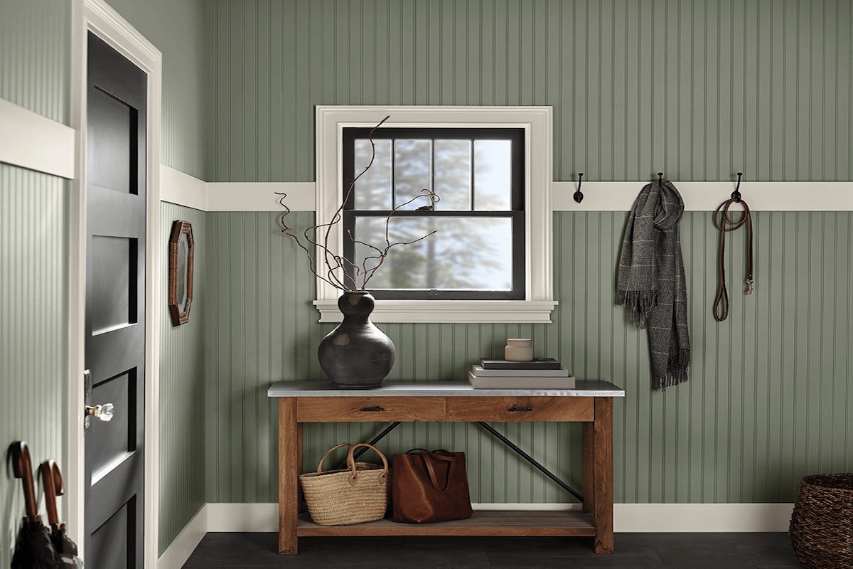 A small hallway with a wooden entry table painted in Sherwin Williams' Evergreen Fog paint color.