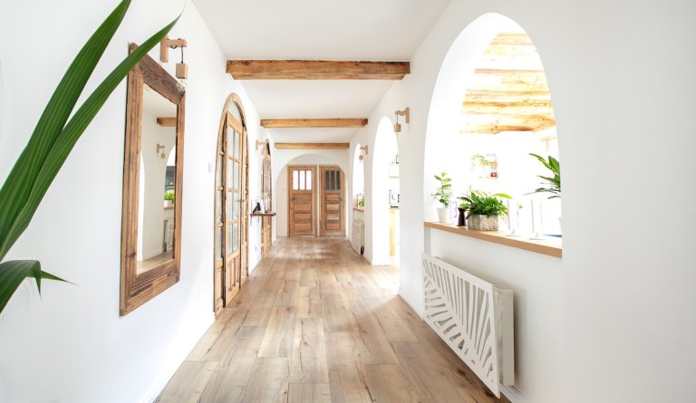 A bright white hallway with light wooden accent beams.