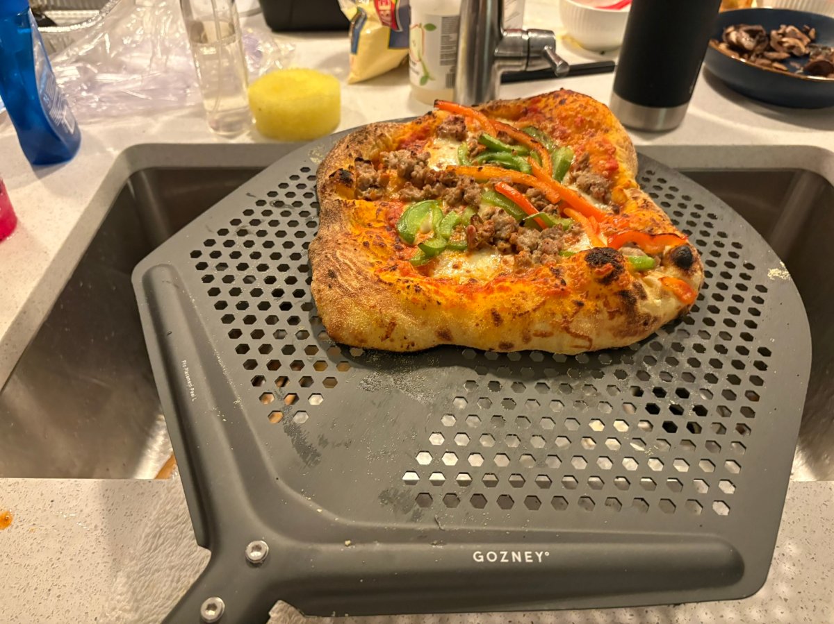 A pizza on a peel after coming out of a gozney pizza oven