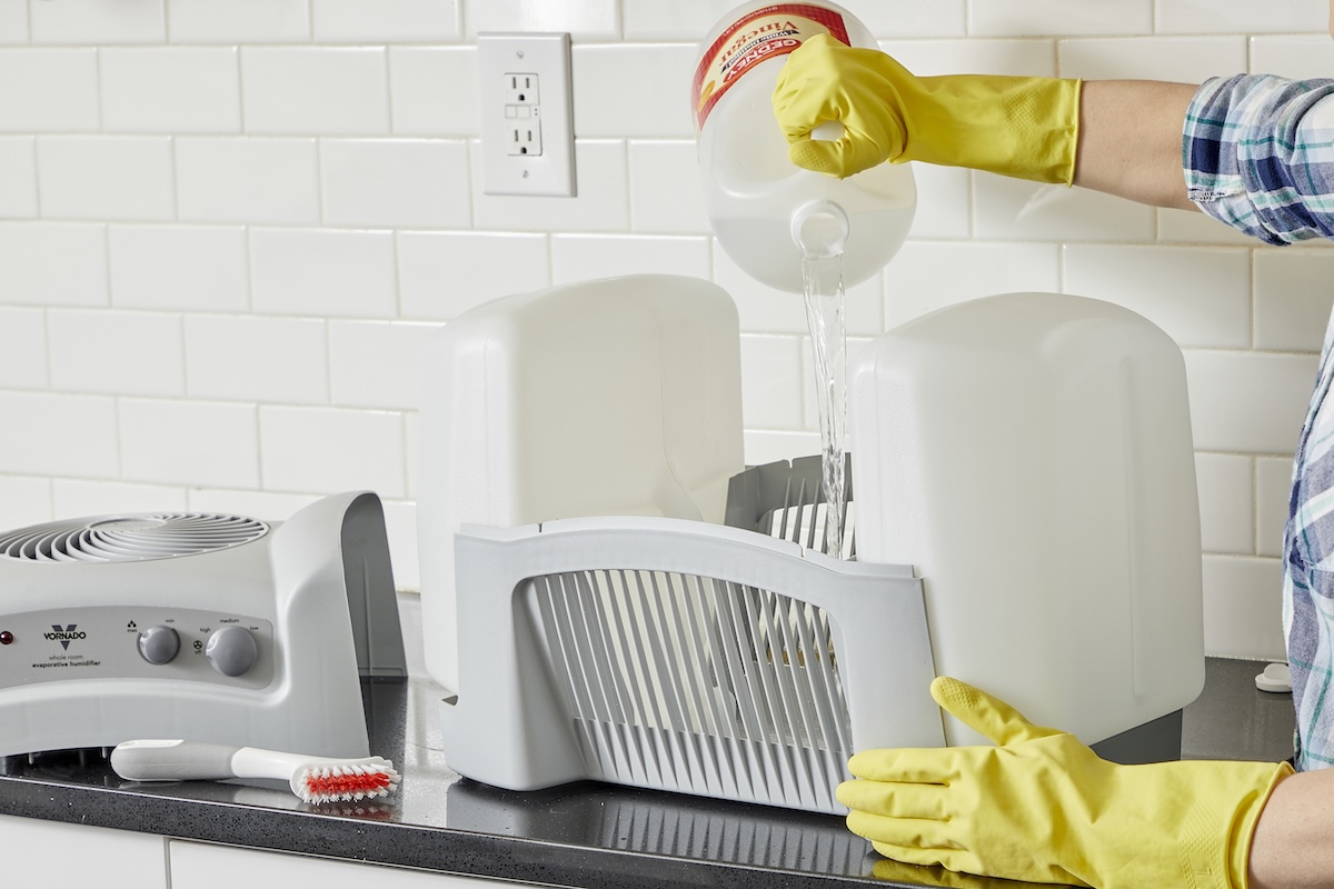 Woman uses white vinegar to clean the inside of a humidifier.