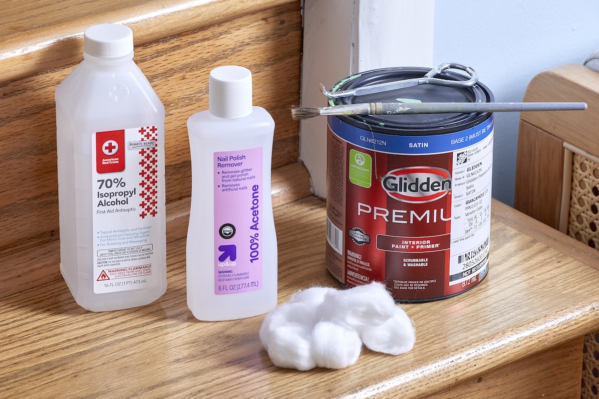 Isopropyl alcohol, nail polish remover, a gallon of paint and cotton balls are positioned on an interior wooden staircase.