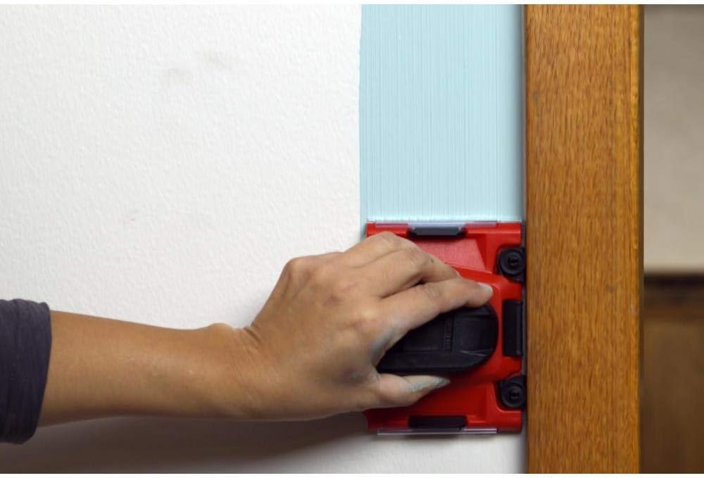 Person uses Shur-Line paint pad edger to paint blue paint next to a wood door frame.