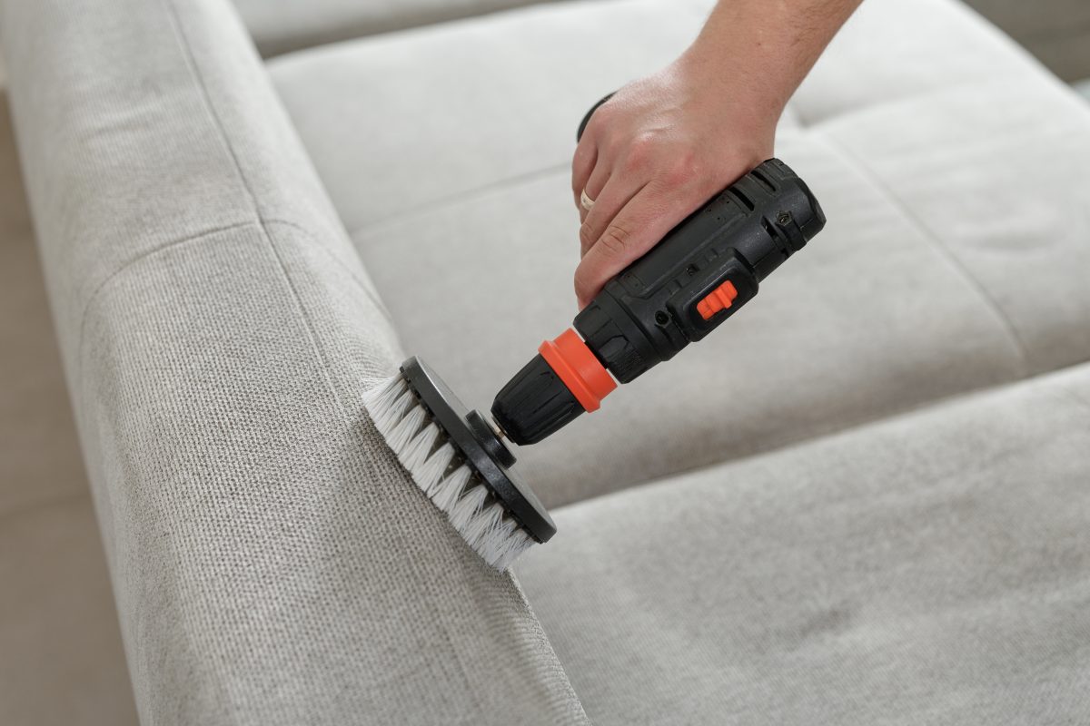 Mechanical brushing of sofa upholstery using drill brush attachment.