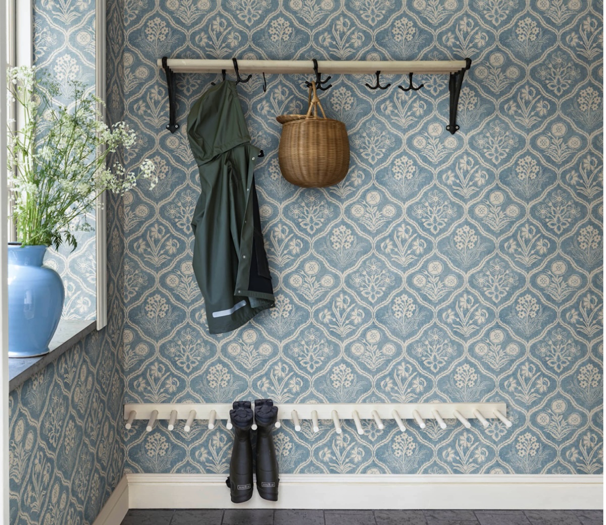 A hallway with a coat rack covered in Sandberg Wallpaper's "Rosa, Blue." 