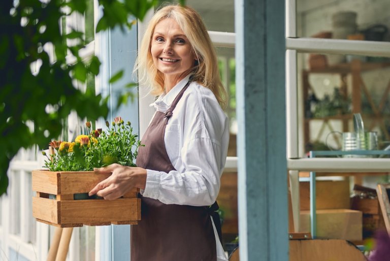 A smiling attractive female with marigolds and gazanias.