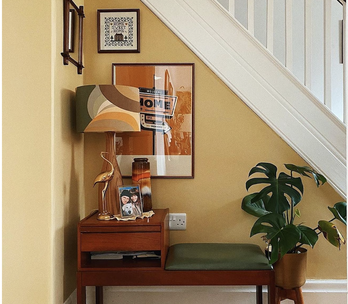 A yellow hallway under a staircase painted in Farrow & Ball's paint color "Hay."
