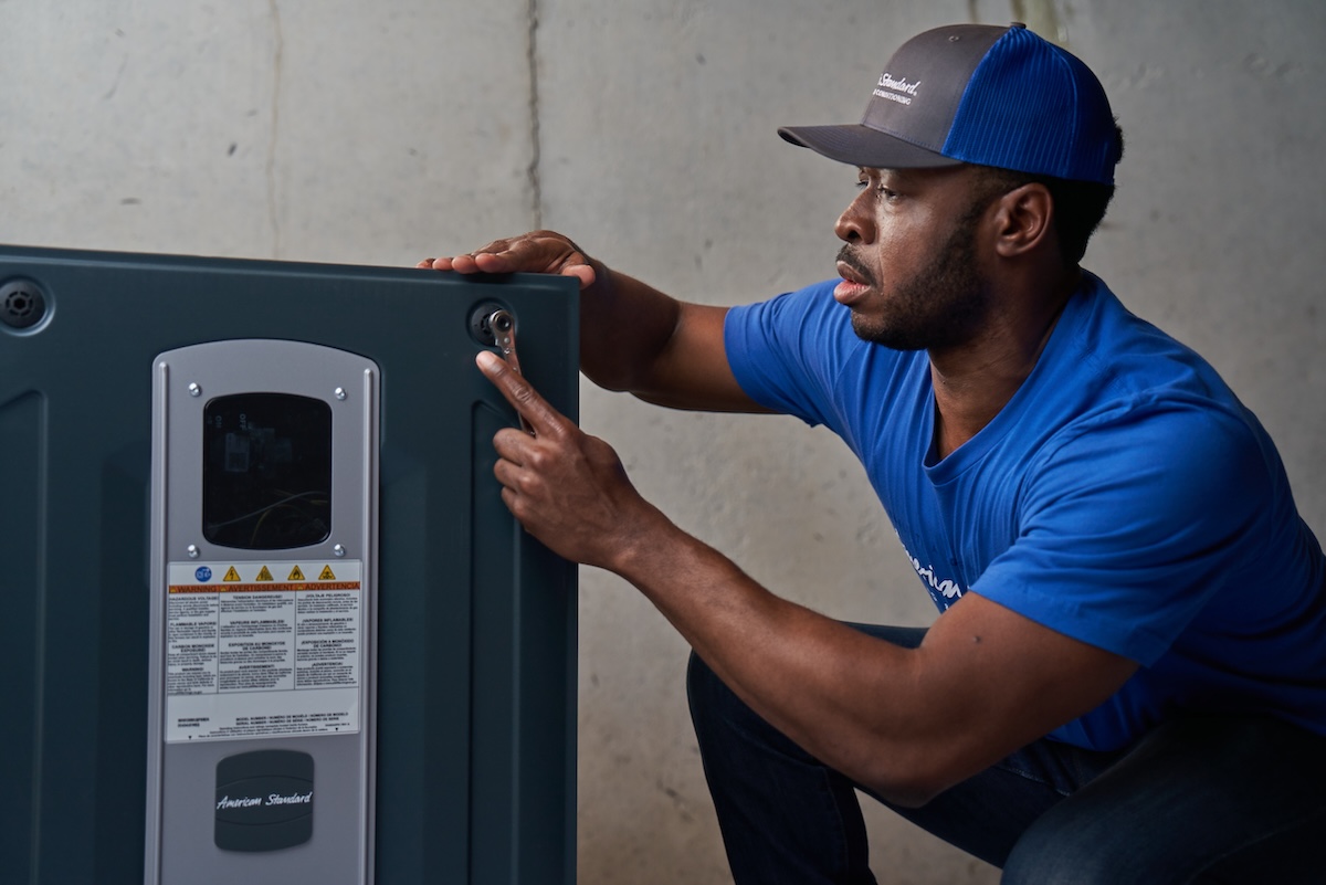 An American Standard heat pump technician working on a unit for installation.
