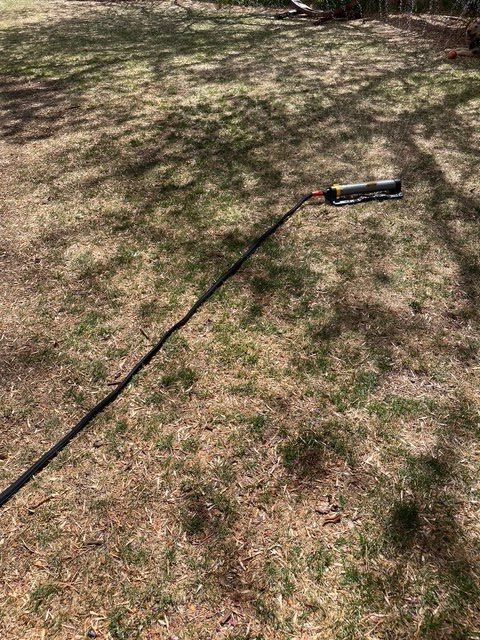The Black+Decker 25-Foot Expanding Garden Hose hooked up to a lawn sprinkler during testing