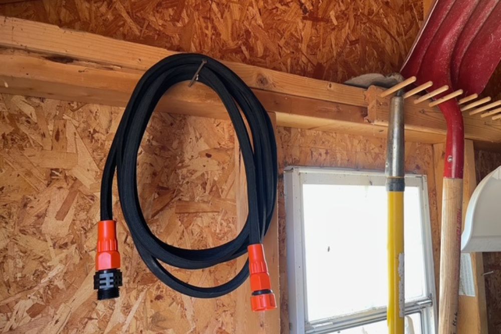 The Black+Decker 25-Foot Expanding Garden Hose hanging in a shed after use
