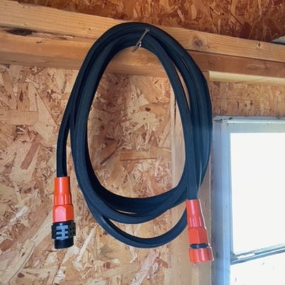 The Black+Decker 25-Foot Expanding Garden Hose hanging in a shed after testing