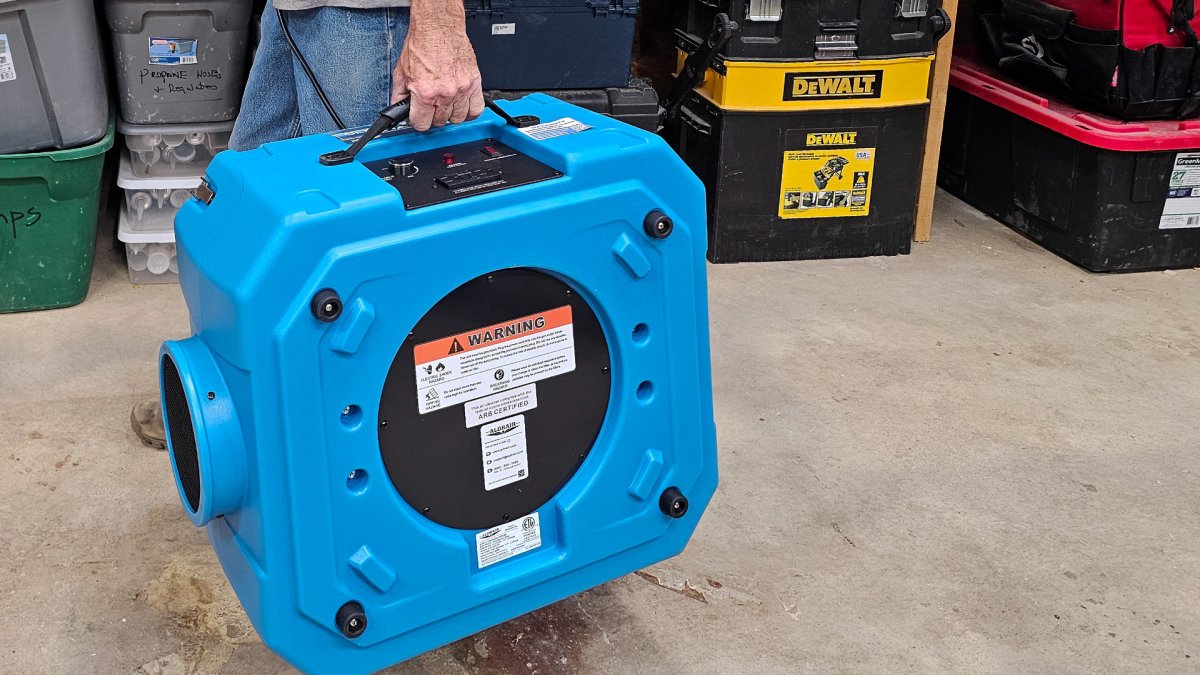 Carrying the AlorAir CleanShield HEPA 550 Air Scrubber via its handle during testing