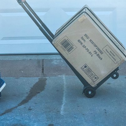 The DiamondForge Folding Hand Truck in use moving a large box during testing
