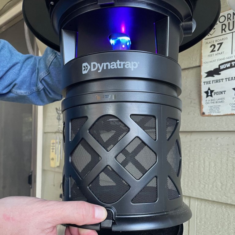 A person opening the collection basket on the Dynatrap 1-Acre LED Mosquito and Insect Trap