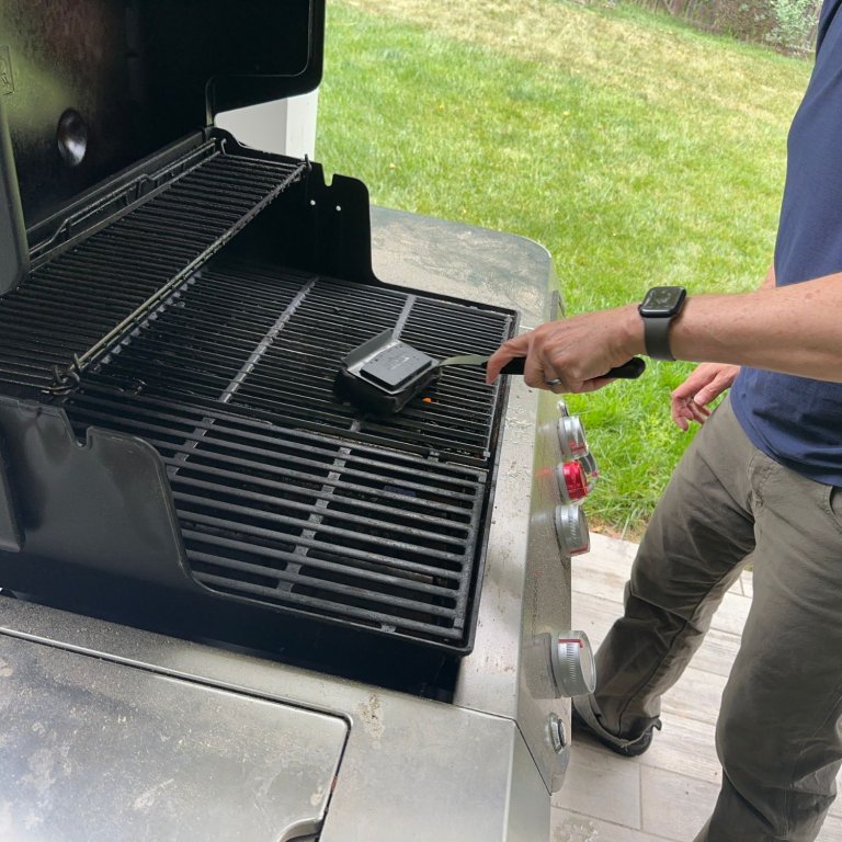 A product tester using the GrillArt SteamWizards Steam-Cleaning Grill Brush to clean grill grates