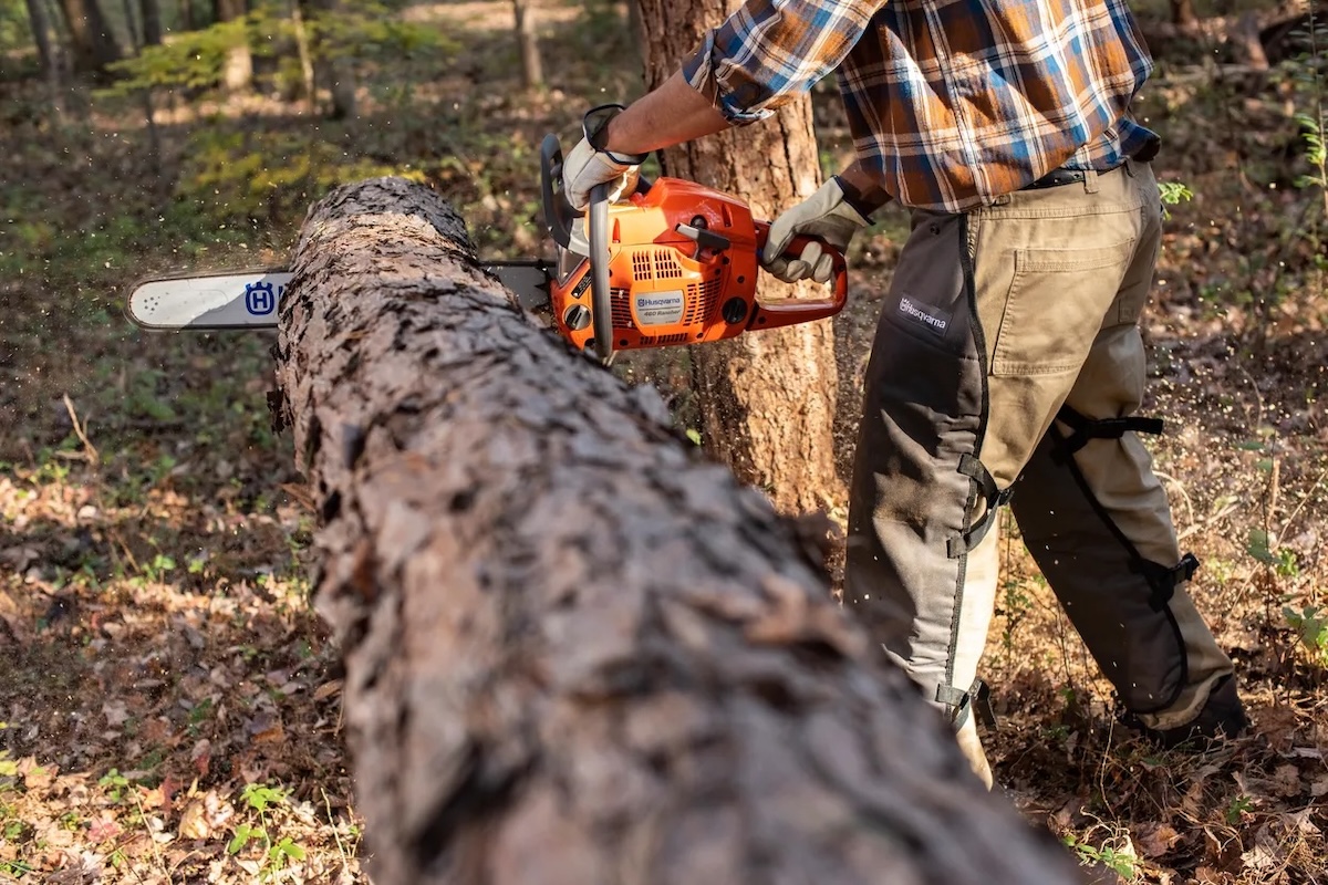 A person using the Husqvarna 460 Rancher Gas Powered Chainsaw to cut rounds from a felled tree