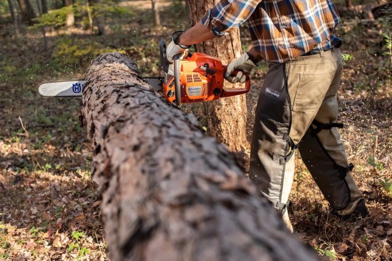 A person using the Husqvarna 460 Rancher Gas Powered Chainsaw to cut rounds from a felled tree