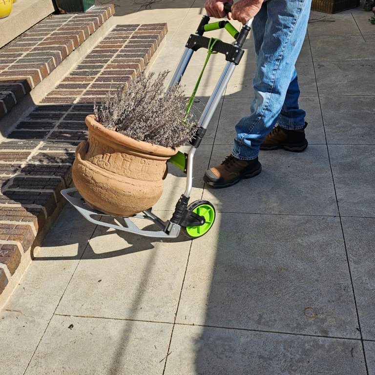 A person using the Leeyoung Folding Hand Truck to move a heavy planter during testing