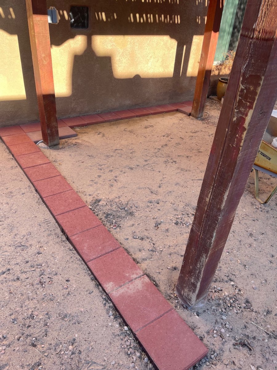 The first row of mixed pavers laid on a patio foundation under a deck.