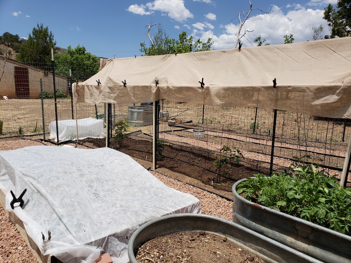 Row covers and shade cloth over vegetable garden beds.