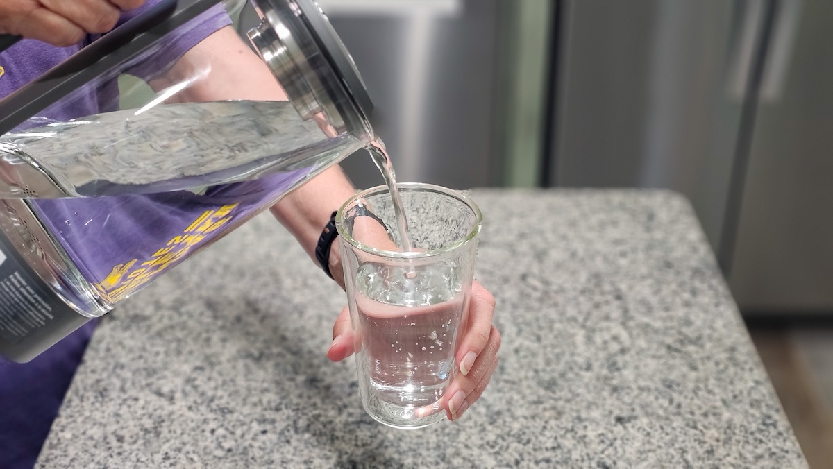 Pouring a glass of crystal clear water from the Waterdrop M6H countertop M6H pitcher